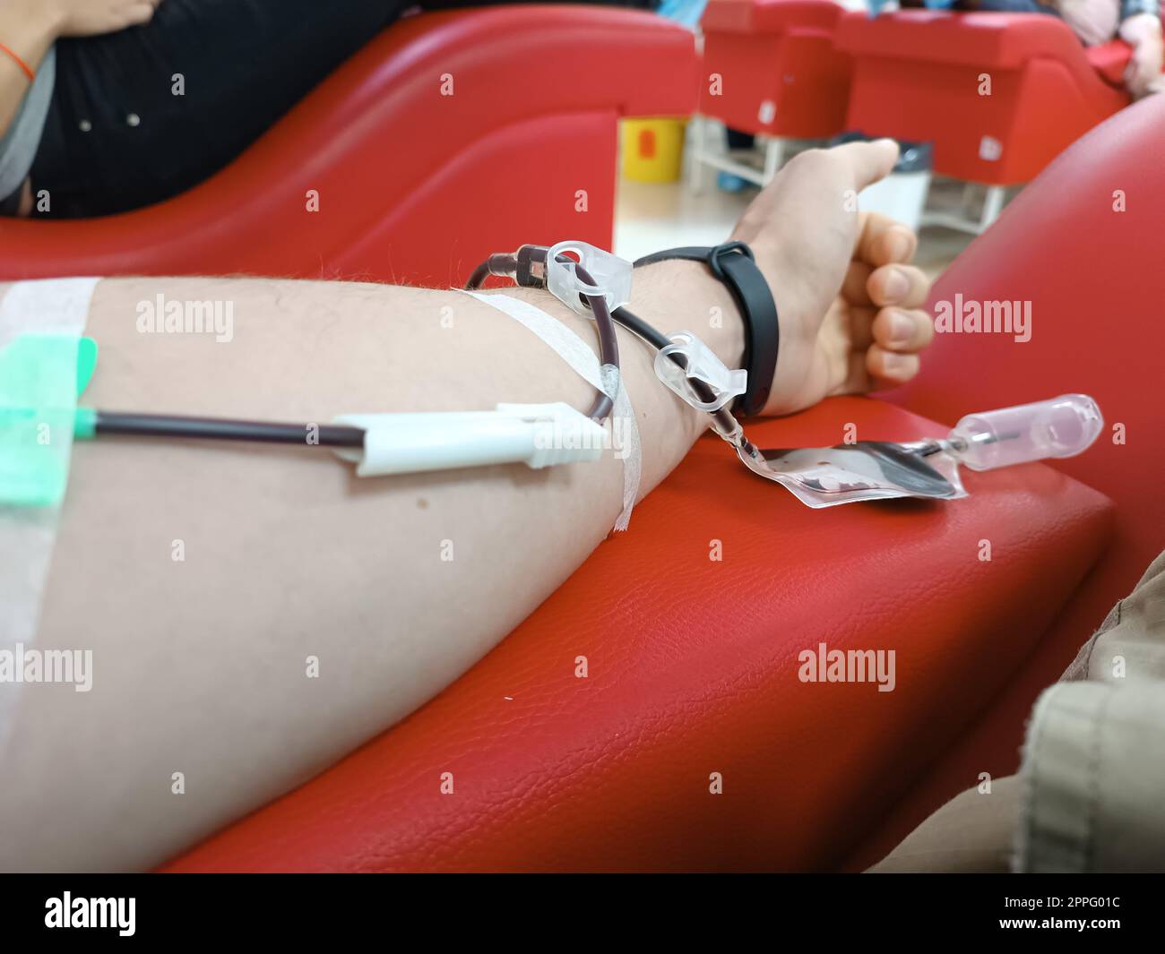 Blutspende, Bluttransfusion, Check spezifiziert, Fasten, medizinische Versorgung. Linker Arm eines jungen Kaukasier-Mannes mit Blut- oder Plasmaspendelausrüstung im Spenderzentrum. Blutspendekonzept. Plasmaspendekonzept. Konzept „Leben retten“. Stockfoto