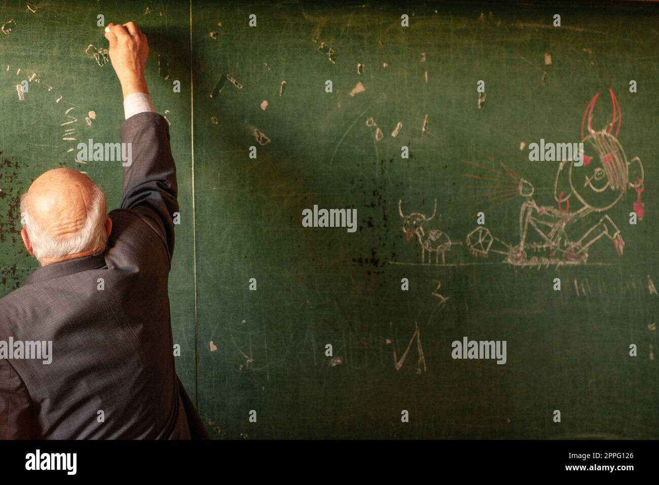 Lehrer an der Schule schreibt auf die Tafel, lustiges Bild. Stockfoto