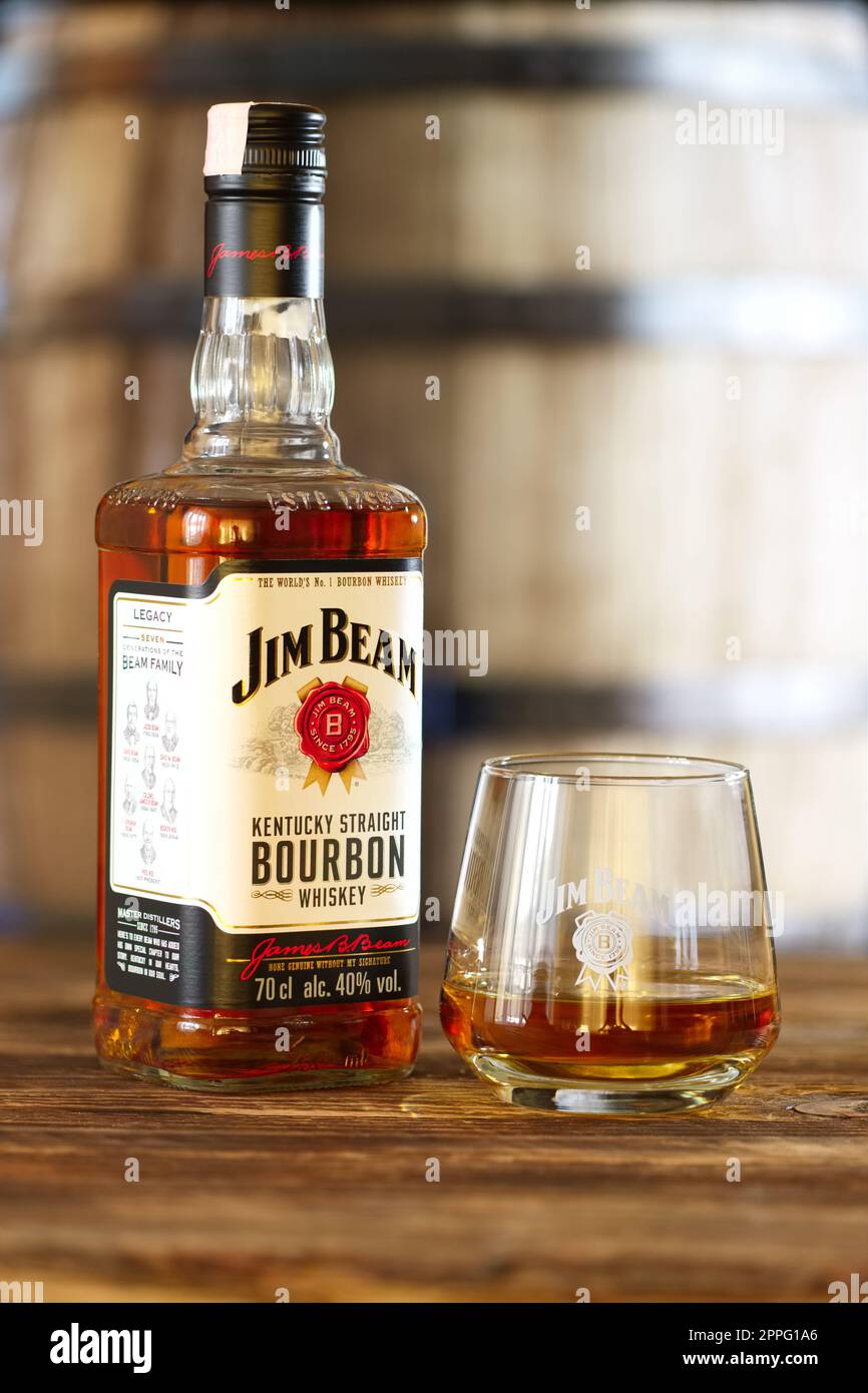März 28, 2019, Minsk, Belarus - Flasche Kentucky straight Bourbon Whiskey mit Glas auf Holztisch mit Faß auf Hintergrund Stockfoto