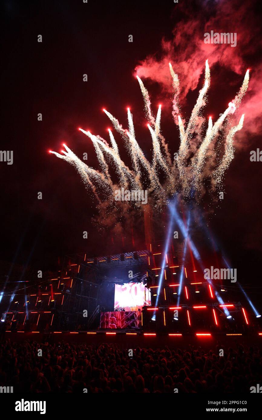 Salut und Feuerwerk auf einer Musikbühne mit Scheinwerfern bei Nacht. Stockfoto