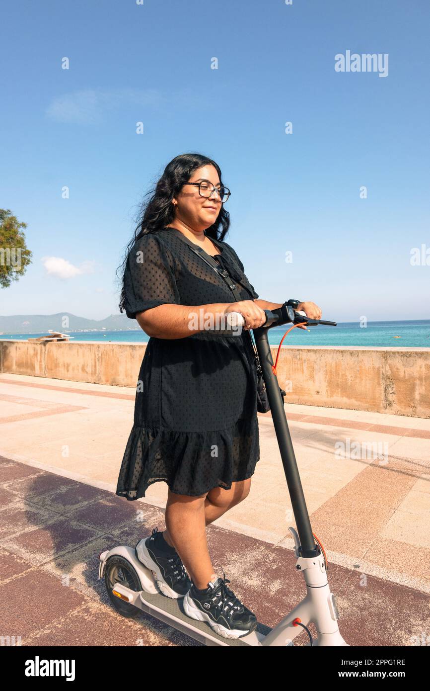 Junge Latina-Frau, fröhliche, positive Lächelfahrer-Wochenendreise mit dem Motorroller Stockfoto