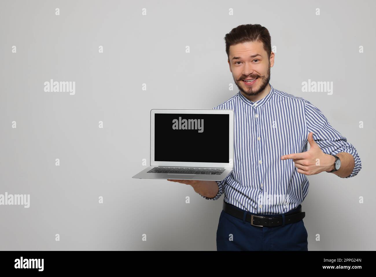 Emotionaler Mann, der auf einen Laptop zeigt, auf hellgrauem Hintergrund. Platz für Text Stockfoto