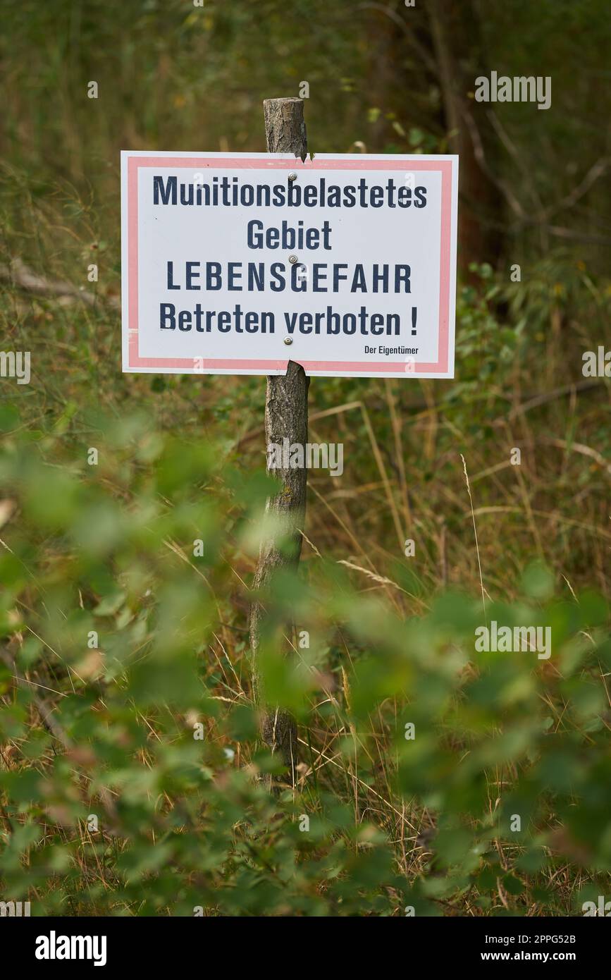 Verbotsschild in einem Wald in Deutschland. Übersetzung: Munitionskontaminierter Bereich, Lebensgefahr, kein Eindringen Stockfoto