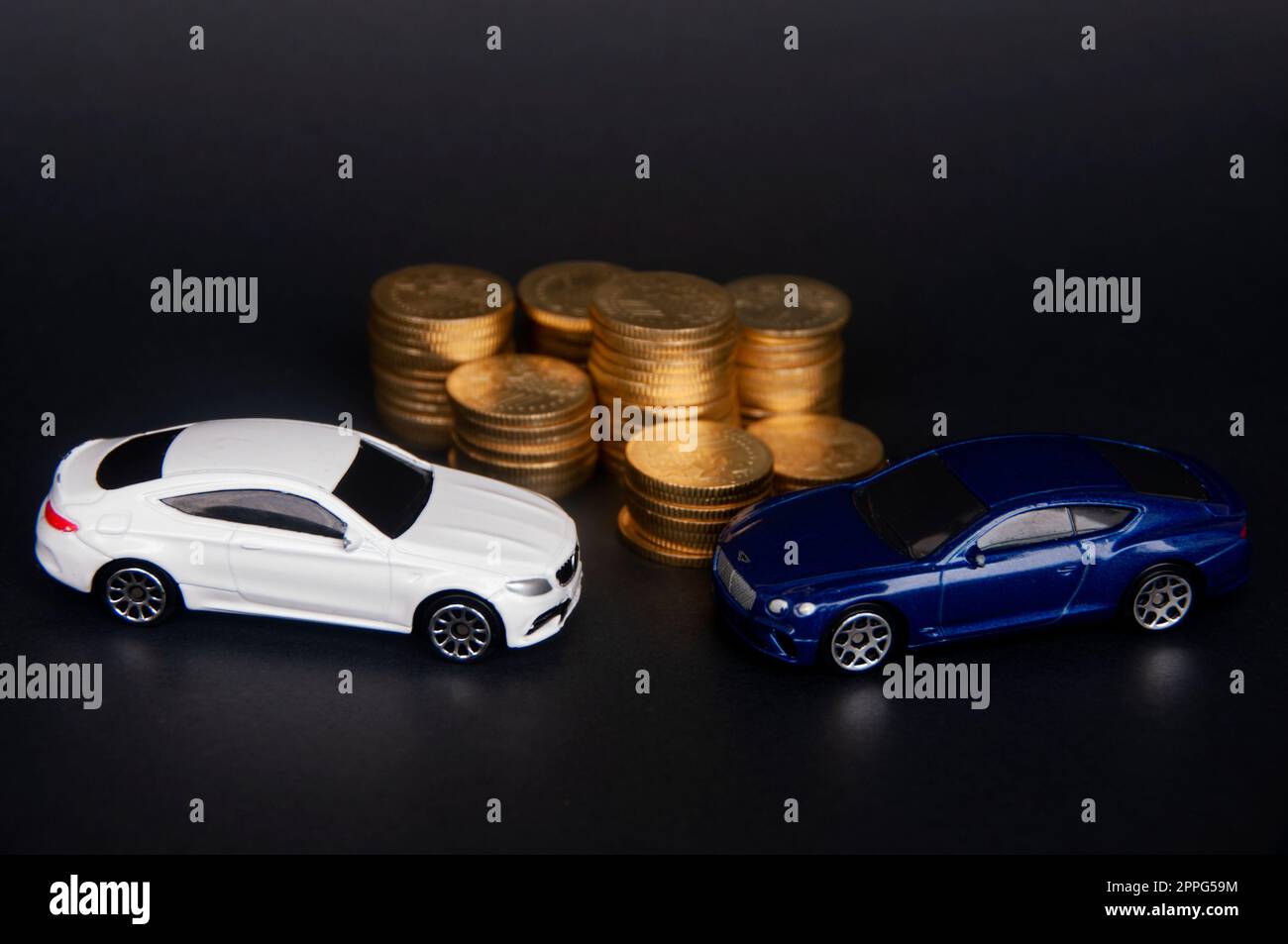 Kuala Lumpur, Malaysia - Juli 2022 : Miniatur-Spielzeugauto von Mercedes AMG und Bentley Continental GT mit Goldmünzen auf schwarzem Einband. Stockfoto