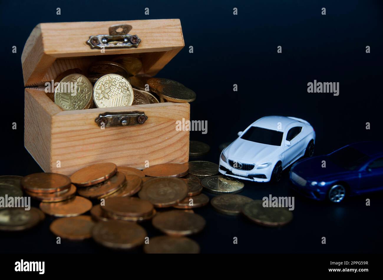 Kuala Lumpur, Malaysia - Juli 2022 : Miniatur-Spielzeugauto von Mercedes AMG und Bentley Continental GT mit Goldmünzen und Schatztruhe auf schwarzem Hintergrund. Stockfoto