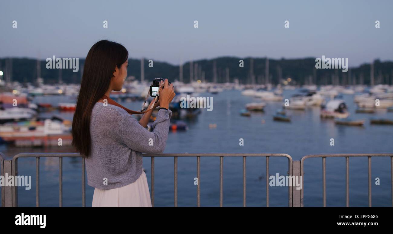 Eine Frau fotografiert mit der Kamera am Pier Stockfoto