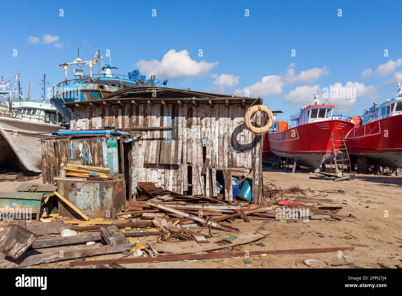 Schäbiges kleines Holzgebäude mit vielen Brettern und alte rostige Schiffe in alten Werften Stockfoto