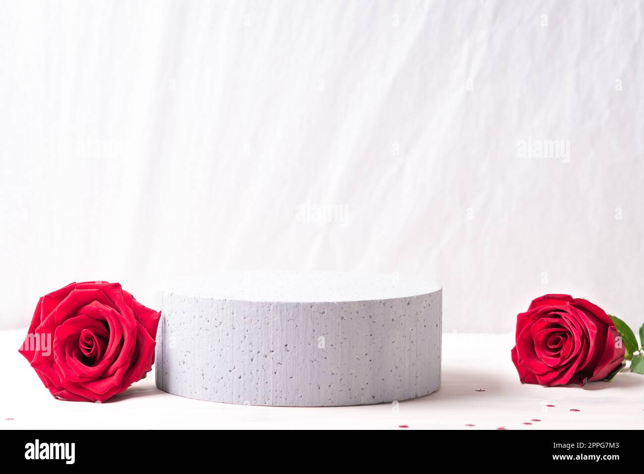Leeres Podium und rote Rosen für die Produktpräsentation. Frische Rosenblumen und Betonsockel, Kopierbereich. Konzeptbühne für Kosmetik, parfum oder Stockfoto