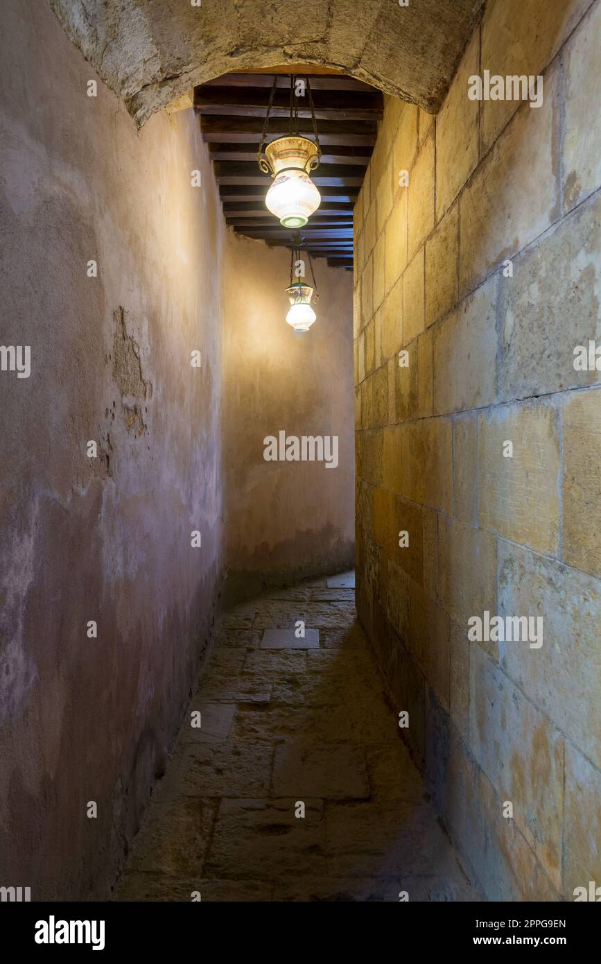 Korridor mit dunklen gewölbten Steinmauern und Holzdecke, die von alten Straßenlaternen aus arabischem Glas beleuchtet werden Stockfoto