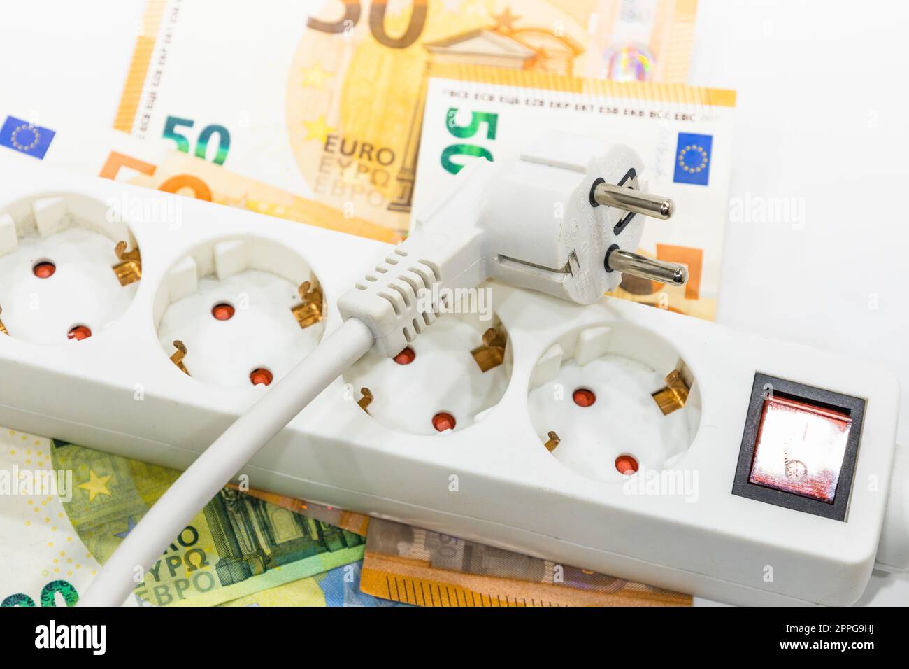 Steckdosenleiste und Euro-Banknoten. Konzept der steigenden Strompreise Stockfoto