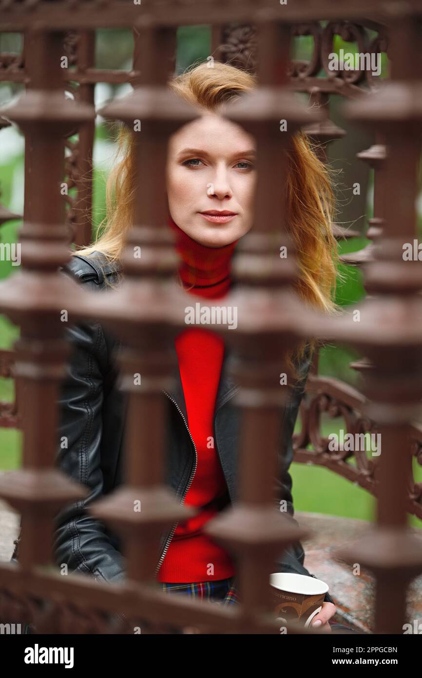 Porträt einer Frau mit rotem Haar durch das Geländer Stockfoto