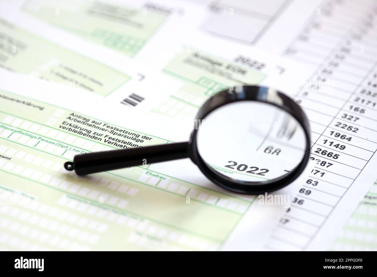 Verschiedene deutsche Steuerformulare und Lupe mit 2022-Aufschrift. Der Begriff der steuerpflichtigen Perion Stockfoto