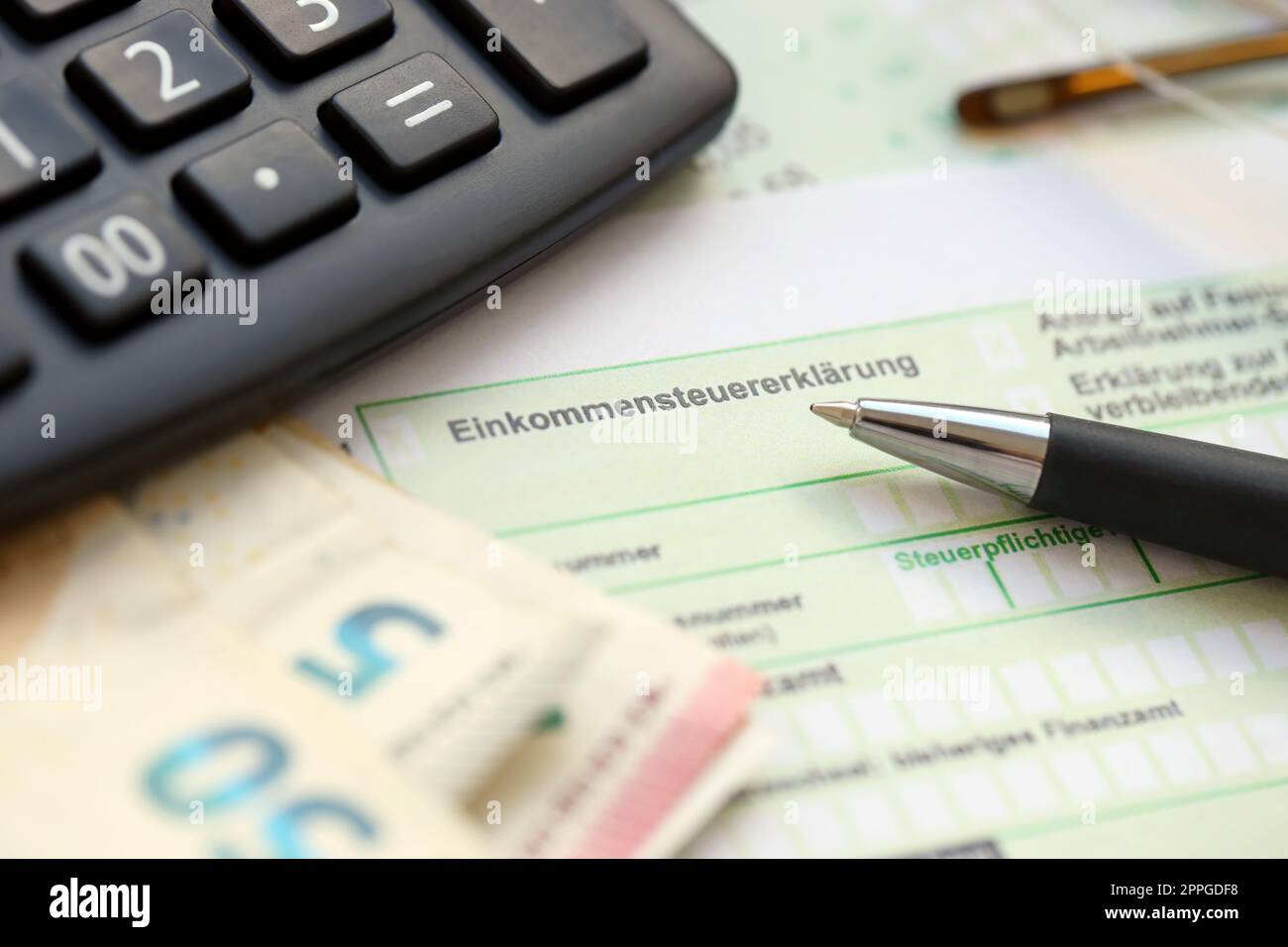 Das deutsche Einkommensteuerformular mit Stift- und euro-Scheinen liegt auf dem Tisch des Buchhalters. Steuerzahler in Deutschland, die Steuern in Euro zahlen Stockfoto