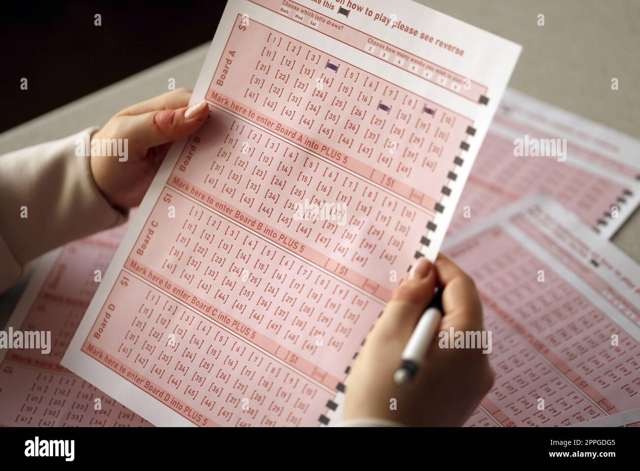 Ein Lotterielos ausfüllen. Eine junge Frau spielt im Lotto und träumt davon, den Jackpot zu gewinnen Stockfoto