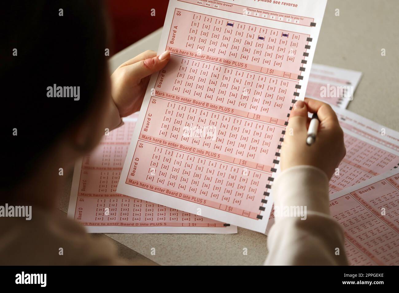 Ein Lotterielos ausfüllen. Eine junge Frau spielt im Lotto und träumt davon, den Jackpot zu gewinnen Stockfoto