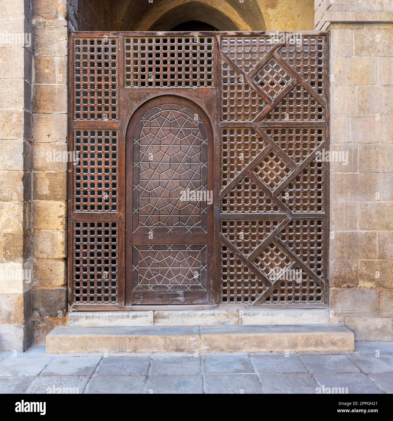 Verblüffende Holzwand, auch bekannt als Mashrabiya, mit kunstvoll verzierter Holztür Stockfoto