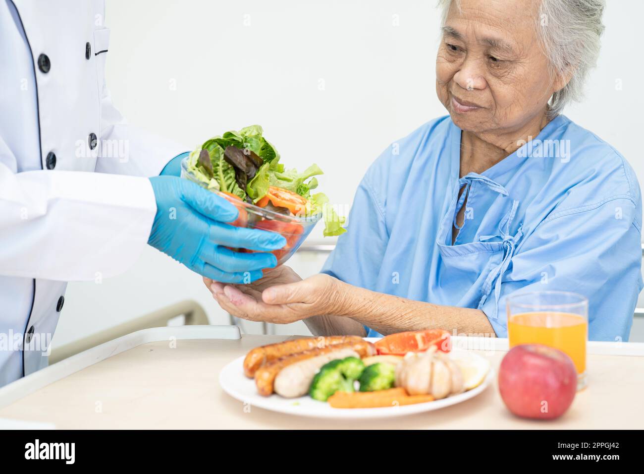 Asiatische Seniorin oder ältere Frau Patientin isst Frühstück und Gemüse gesunde Lebensmittel mit Hoffnung und glücklich während sie im Krankenhaus sitzen und hungrig im Bett. Stockfoto