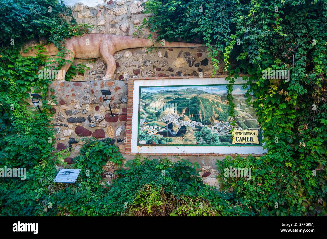 CAMBIL, SPANIEN - 14. OKTOBER 2021: Steinmauer in Cambil, Andalusien, Spanien, mit einem Mosaik aus Fliesen mit Blick auf die Stadt darüber gibt es eine Nachbildung eines Reptils der Brachychirotherium-Art, die vor etwa 225 Millionen Jahren entstanden ist Stockfoto
