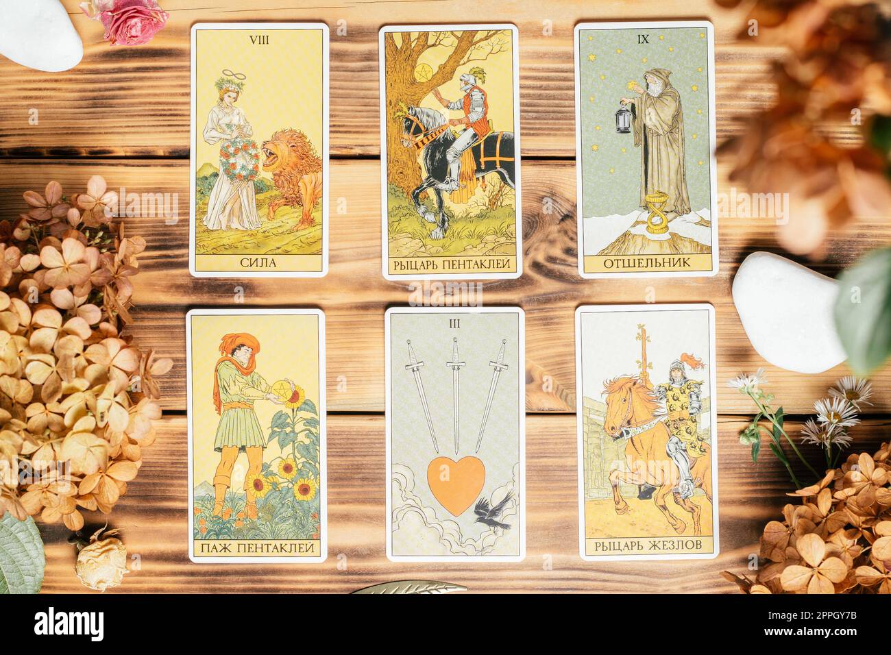 Tarot-Karten mit Steinen, Herbstpflanzen und Accessoires sind mit der Vorderseite nach oben auf der Holzfläche verteilt. Minsk, Belarus, 11.10.2021 Stockfoto