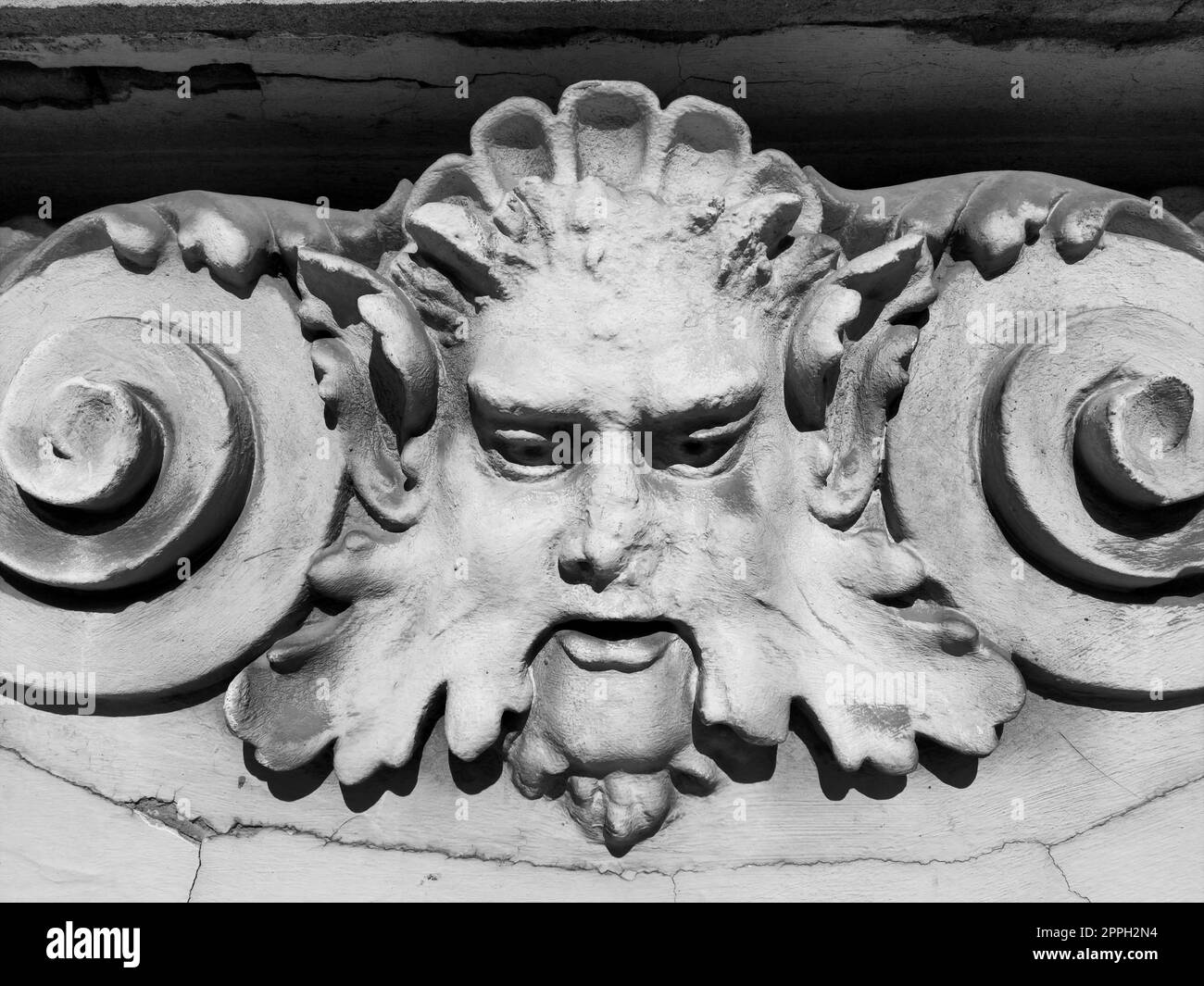 Dekorative Details an der Fassade. Relief an der Fassade eines Gebäudes. Stuckverzierung in Form eines Männerkopfes mit Locken, Schnurrbart und Locken an den Seiten. Hochentlasteter Beton. Stockfoto