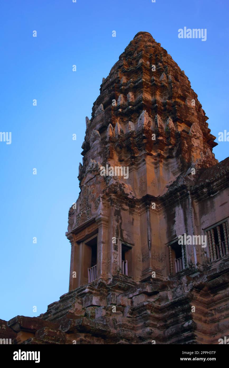 Angkor Wat, in Kambodscha. Niedriger Winkel Blick auf einen der zentralen Türme bei Sonnenuntergang vor blauem Himmel. Stockfoto