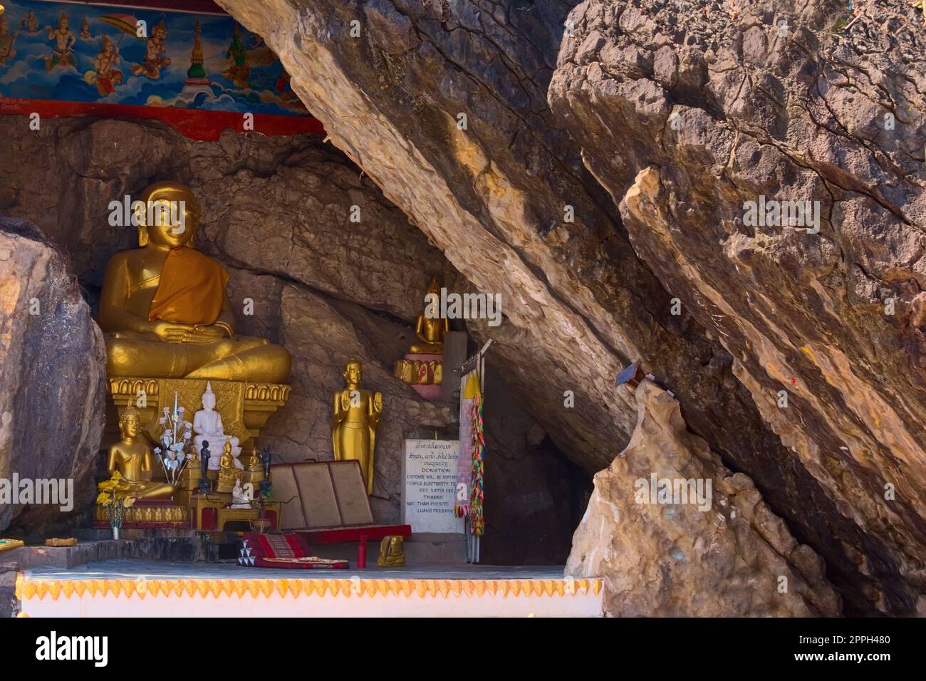 Goldene Buddha-Statue auf einer Felsenspalte am Mount Phou Si in Luang Prabang, Laos. Der Eingang des Höhlenschreins ist auf der rechten Seite zu sehen. Stockfoto