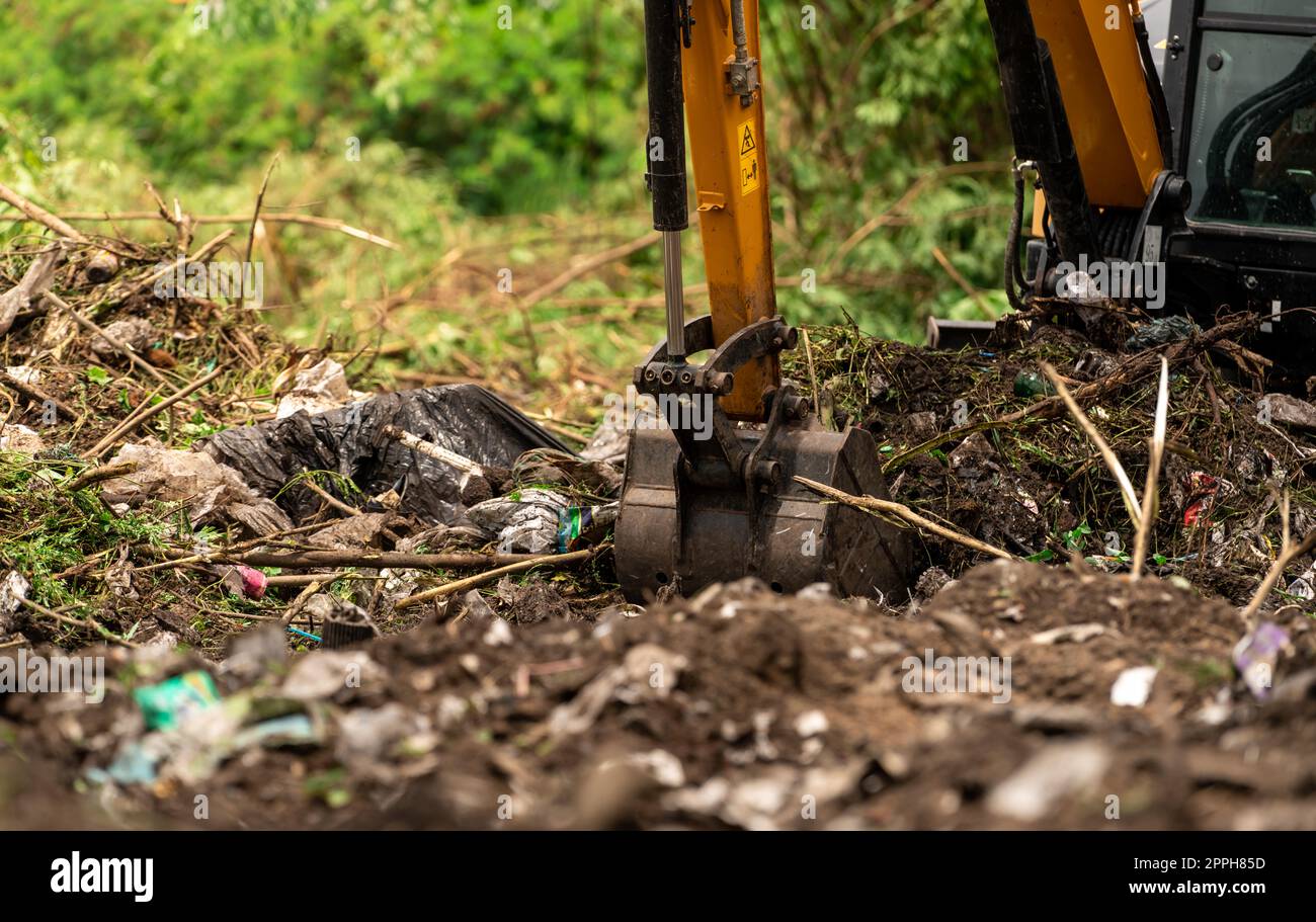 Baggerlader Graben von Erde auf der Baustelle. Schaufel mit Baggerladerboden zum Graben. Roden und Roden. Bagger auf Straßenbaustellen. Erdbewegungsmaschine. Ausgrabungsfahrzeug. Erschließung von Grundstücken. Stockfoto