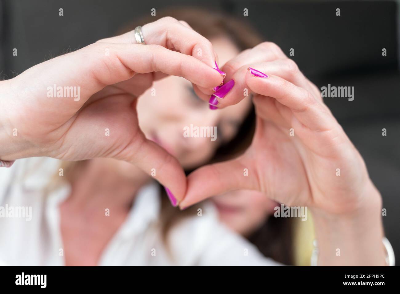 Mutter und ihre kleine Tochter zeigen Herzform mit den Fingern. Stockfoto