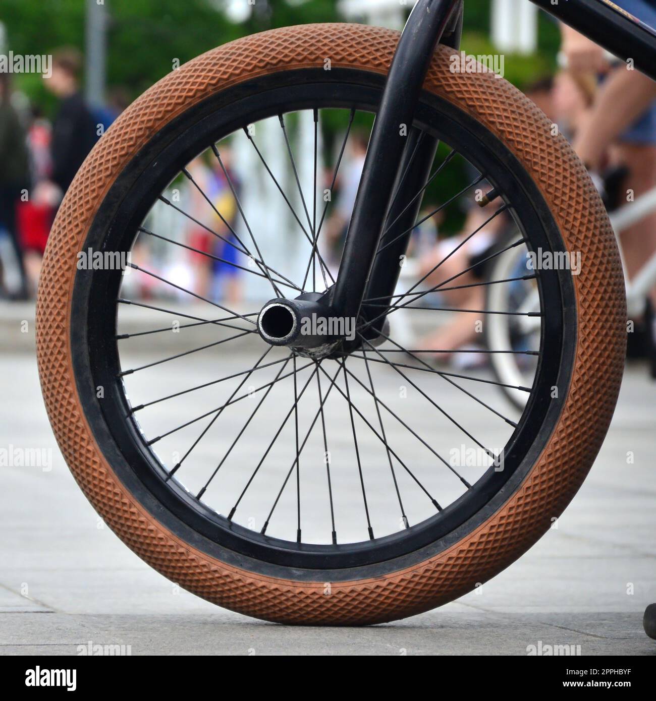 Ein BMX Fahrrad Rad vor dem Hintergrund einer unscharfen Straße mit Radfahren Reiter. Extreme Sport Konzept Stockfoto