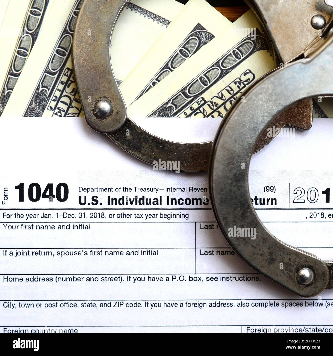 Polizeihandschellen liegen auf der Steuerform 1040. Das Konzept der Probleme mit dem Gesetz nach der Nichtzahlung von Steuern Stockfoto