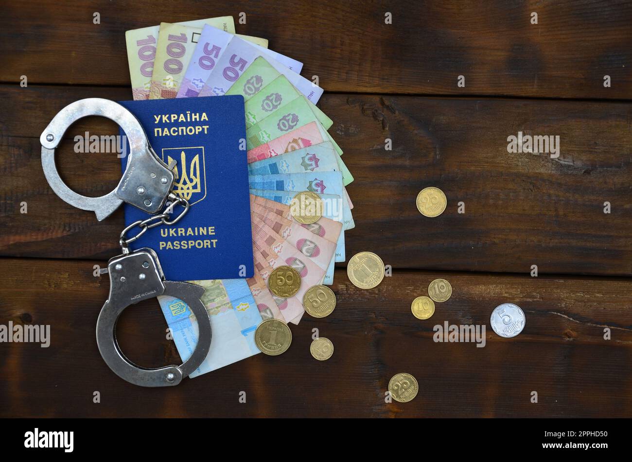 Ein Foto eines ukrainischen ausländischen Reisepasses, eine bestimmte Menge ukrainischen Geldes und Handschellen der Polizei. Das Konzept der Verhaftung ukrainischer illegaler Einwanderer bei dem Versuch, zu bestechen Stockfoto