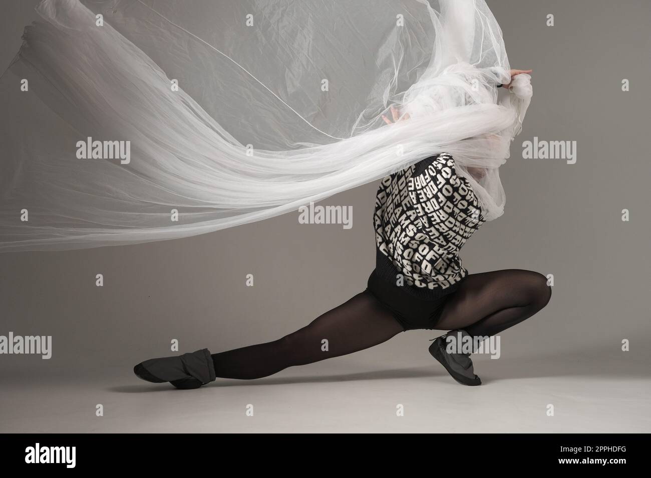 Ballerina mit Seidenstoff, moderne Balletttänzerin mit wellenförmigem weißem Stoff, grauer Hintergrund. Mit Text auf Pullover, VON dem DU TRÄUMST Stockfoto