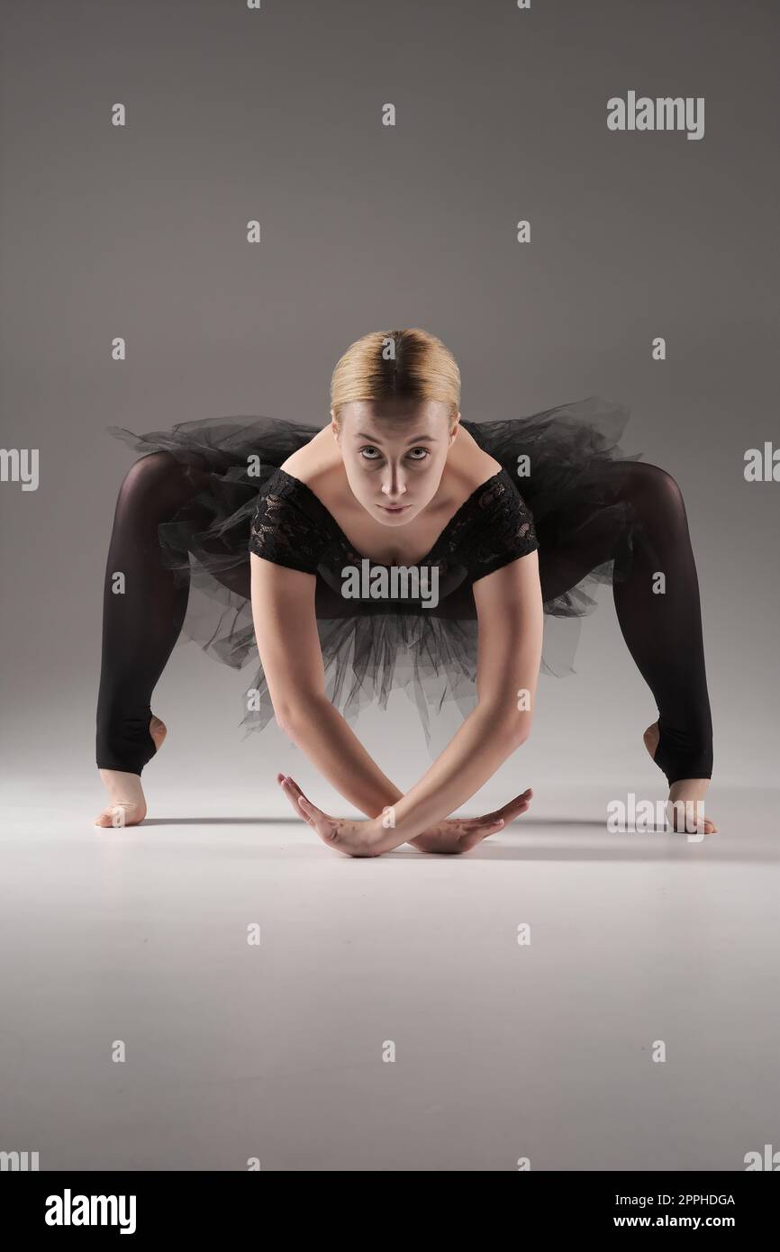 Ballerina tanzt mit Tutu Moderne Balletttänzerin in Tutu, grauer Hintergrund. Tänzerin in schwarzer Kleidung zeigt ihre Flexibilität und posiert im Studio auf grauem Hintergrund Stockfoto