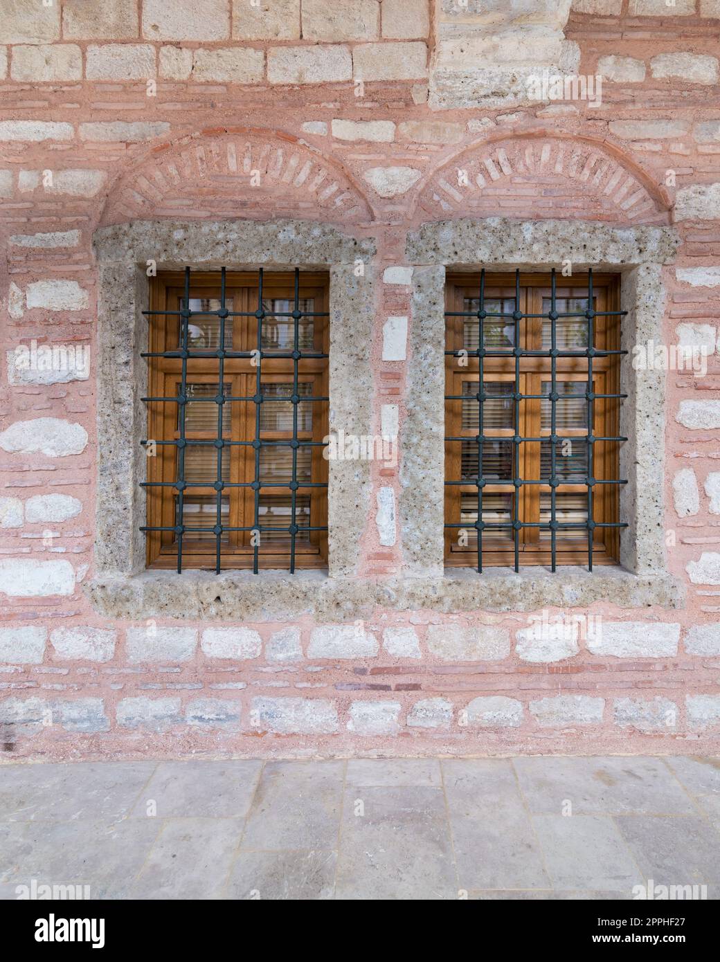 Zwei angrenzende Holzbogenfenster in einer rot-weißen Steinmauer, in der Nähe von Eyup Sultan Mosqoe, Istanbul, Türkei Stockfoto