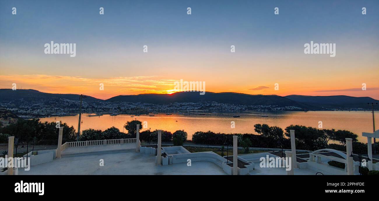 Wunderschöner Sonnenaufgang über den Bergen an der Küste mit antiker griechischer Architektur Stockfoto