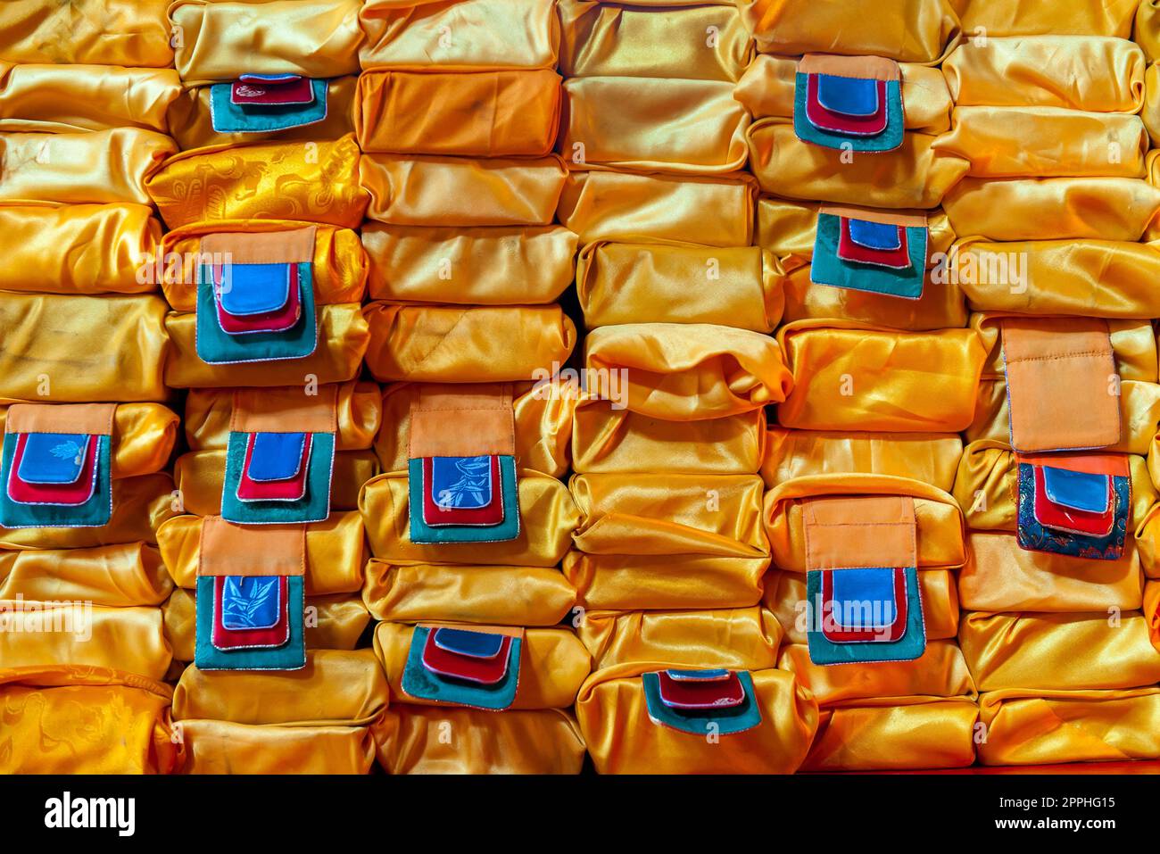 Nahaufnahme eines Stapels von Gebetsbüchern in orangefarbenen Tüchern in einem buddhistischen Kloster in der Mongolei, Zentralasien. Stockfoto
