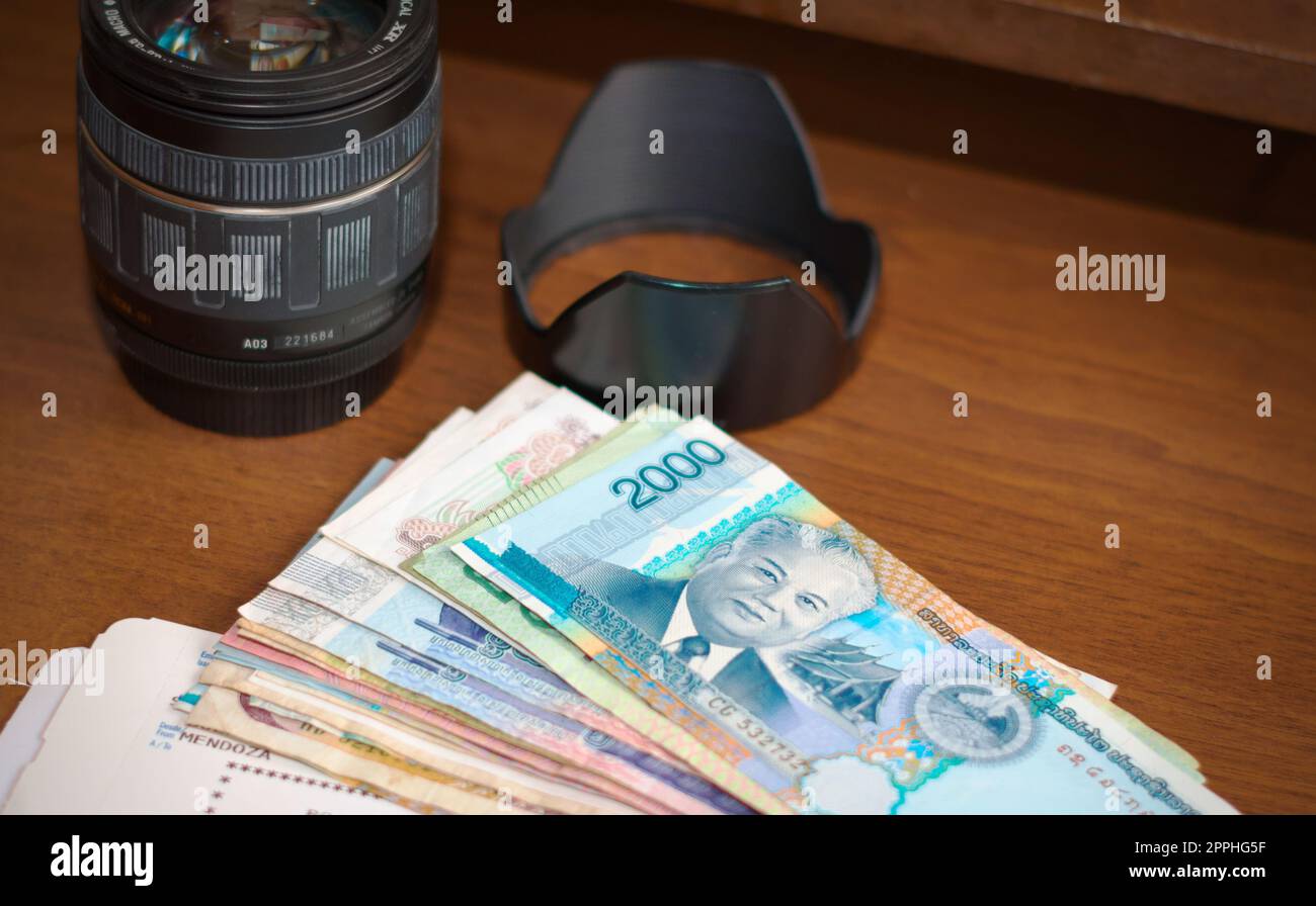 Kameraobjektiv, ausländisches Geld und Bordkarte für Flugzeuge auf einem Holztisch. Tourismus, Urlaub, Reisen Fotografie Ausrüstung. Stockfoto