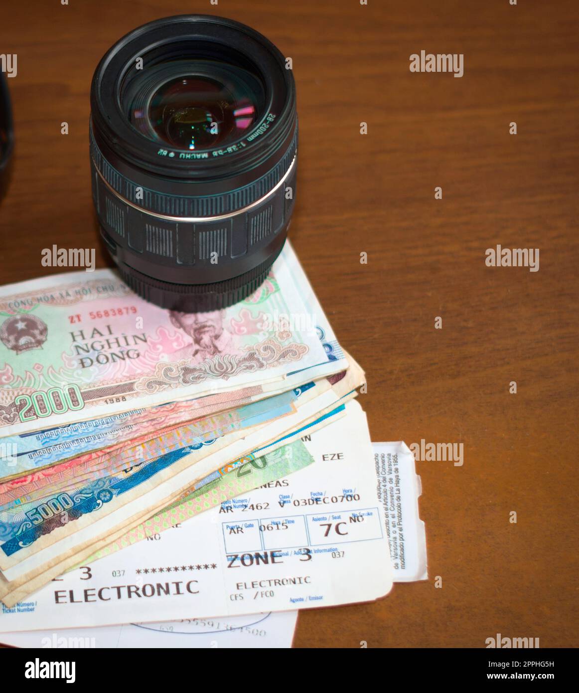 Kameraobjektiv, ausländisches Geld und Bordkarte für Flugzeuge auf einem Holztisch. Tourismus, Urlaub, Reisen Fotografie Ausrüstung. Stockfoto