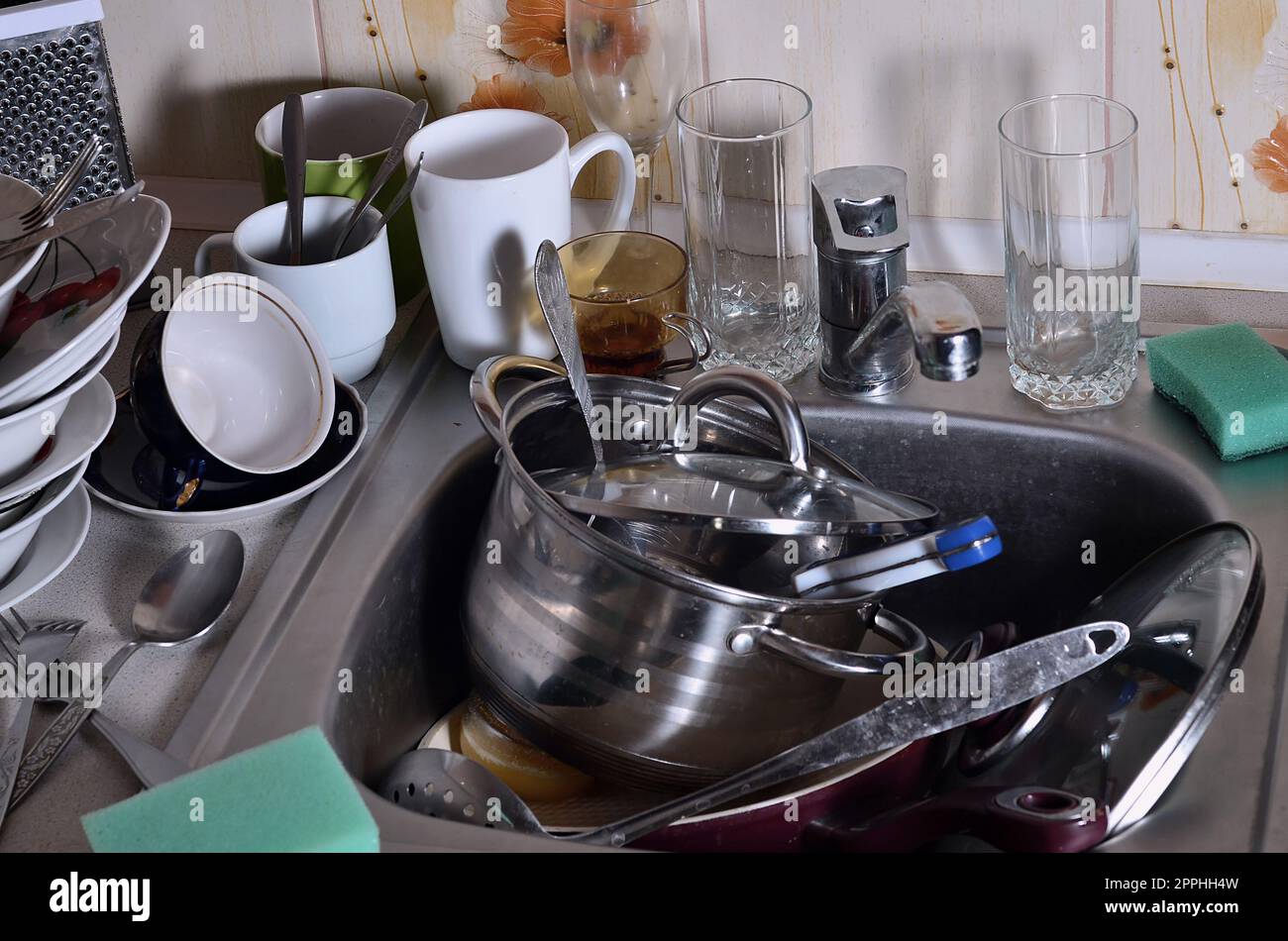 Ein riesiger Haufen ungewaschenes Geschirr im Spülbecken und auf der Arbeitsfläche Stockfoto