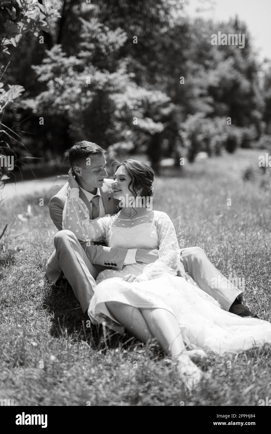 Braut in einem leichten Hochzeitskleid zum Bräutigam im blauen Anzug Stockfoto