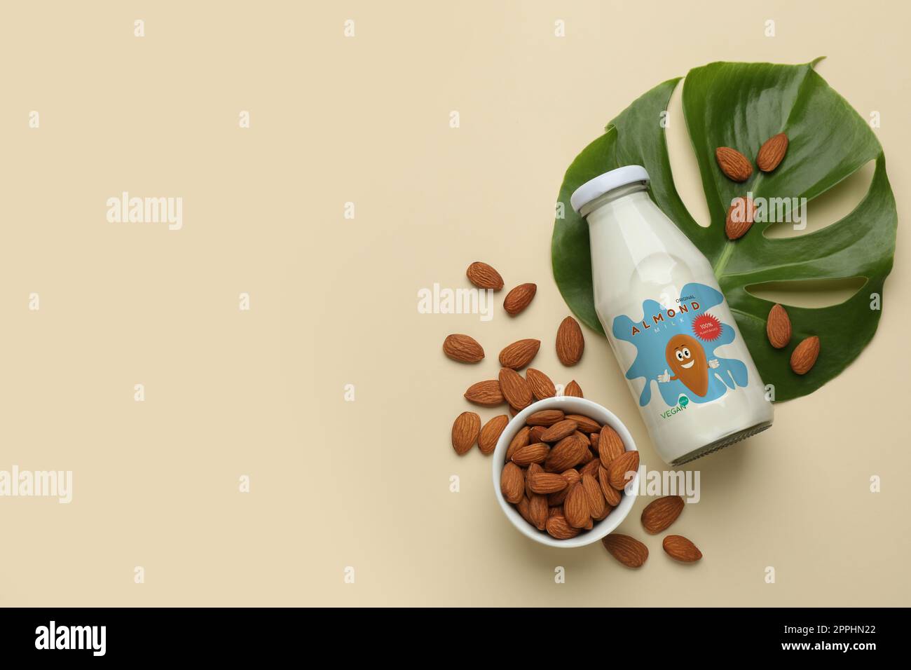Flasche Mandelmilch und Nüsse auf beigefarbenem Hintergrund, flach liegend mit Platz für Text. Veganes Produkt Stockfoto