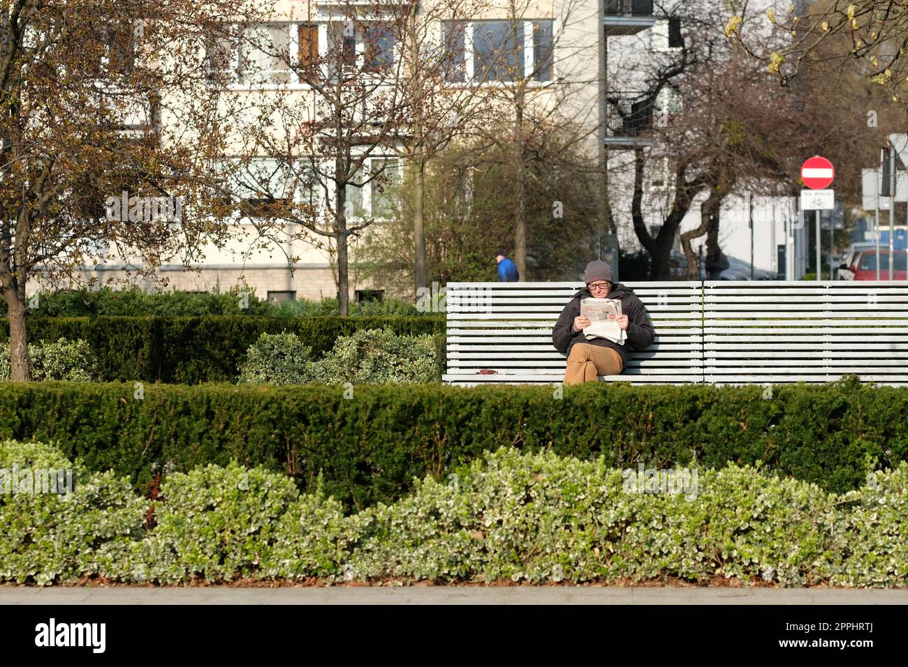 Warschau Polen ein Mann sitzt und liest eine Zeitung auf einer Bank im Garten vor dem POLIN-Museum in der Warschauer Ghetto-Gegend. April 2023 Stockfoto