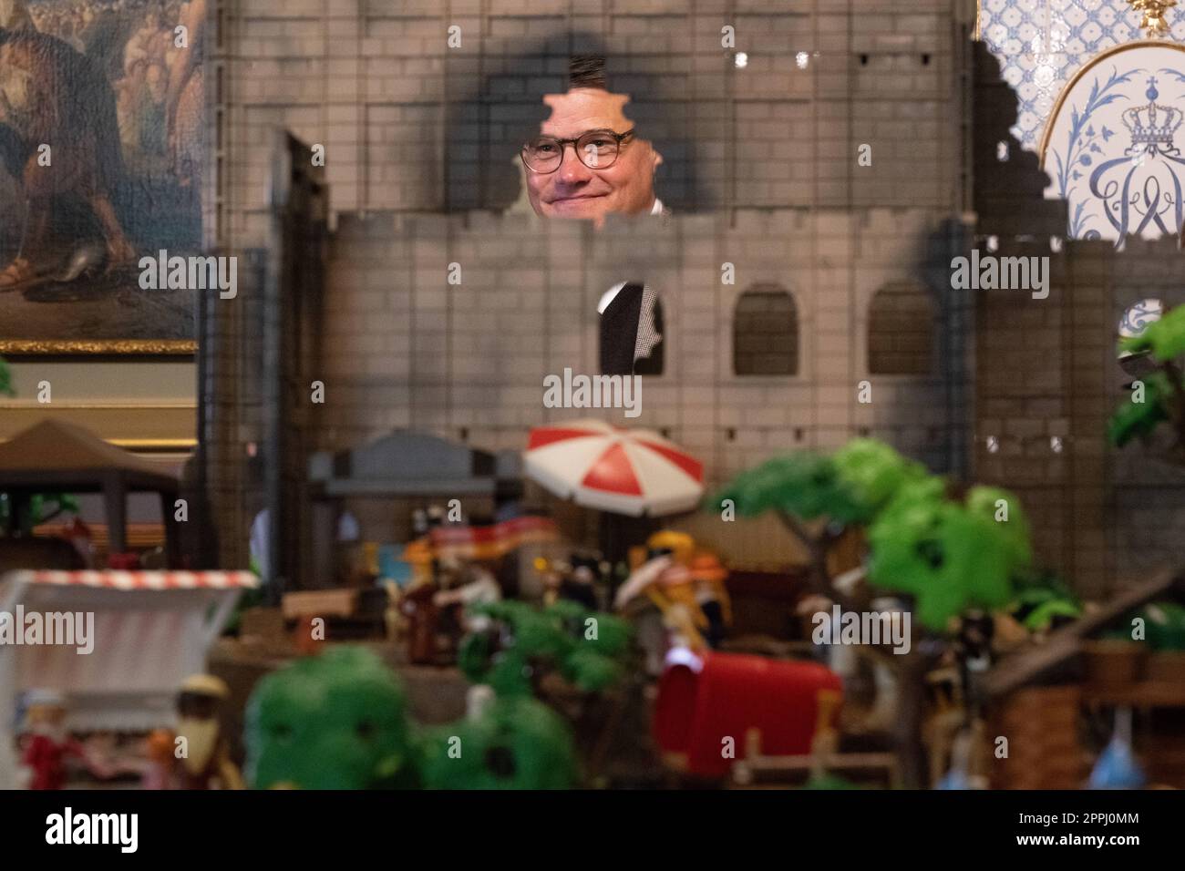 Hanau, Deutschland. 24. April 2023. Boris Rhein (CDU), Ministerpräsident von Hessen, steht hinter einem Playmobil-Diorama des Hambach-Festivals in einer Playmobil-Ausstellung, die 175 Jahre Frankfurts Paulskirche im Hanau History Museum in der Burg Philippsruhe feiert. Die Ausstellung zeigt die Geschichte der deutschen Demokratie in elf Dioramen, die aus Tausenden von Playmobil-Teilen bestehen. Kredit: Sebastian Christoph Gollnow/dpa/Alamy Live News Stockfoto