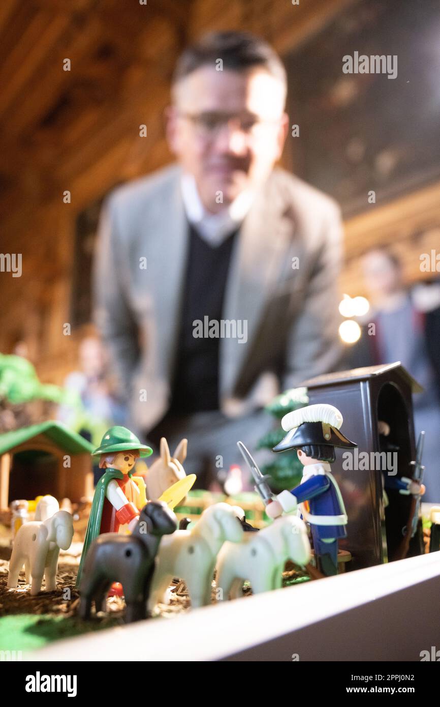 Hanau, Deutschland. 24. April 2023. Boris Rhein (CDU), Ministerpräsident von Hessen, schaut auf die älteste Playmobil-Figur der Ausstellung - ein Schäfer aus dem Jahr 1981 - auf einer Playmobil-Ausstellung, die 175 Jahre Frankfurter St. feiert Paul's Church im Hanau Historical Museum in Philippsruhe Castle. Die Ausstellung zeigt die Geschichte der deutschen Demokratie in elf Dioramen aus Tausenden von Playmobil-Stücken. Kredit: Sebastian Christoph Gollnow/dpa/Alamy Live News Stockfoto