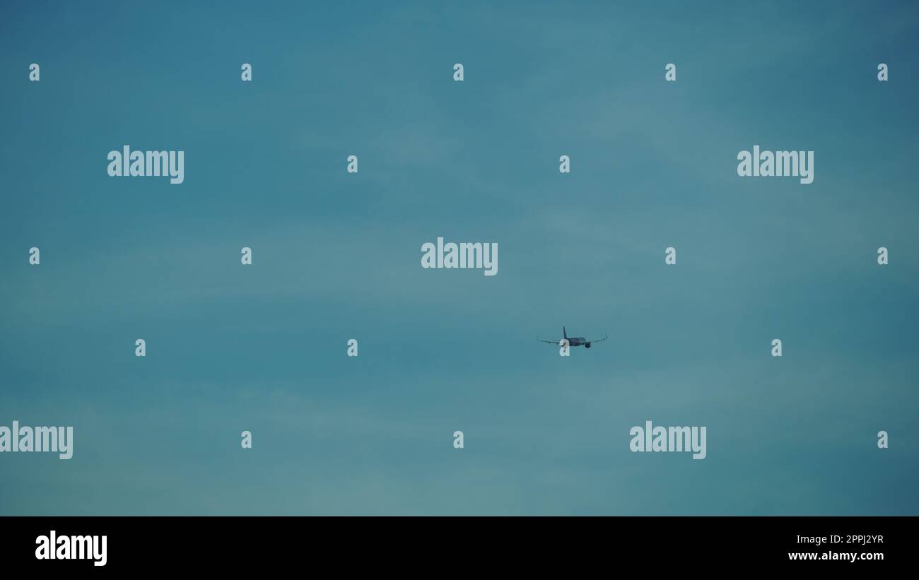 Das Passagierflugzeug fliegt weit weg am dunkelblauen Himmel. Flugzeug in der Luft. Internationaler Passagierluftverkehr Stockfoto
