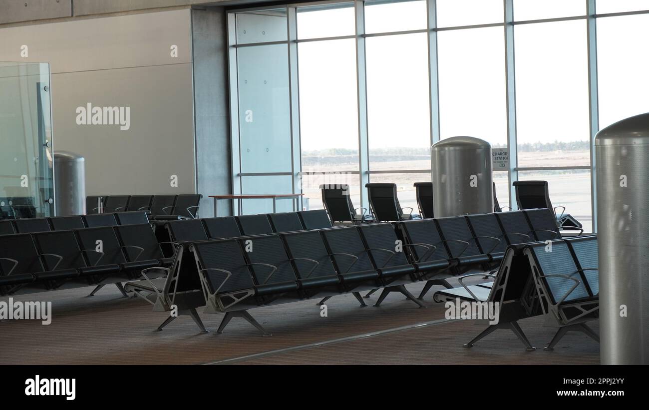 Leere Flughafenterminal-Lounge. Leere Flughafensitze - typische schwarze Stühle beim Boarding warten Stockfoto