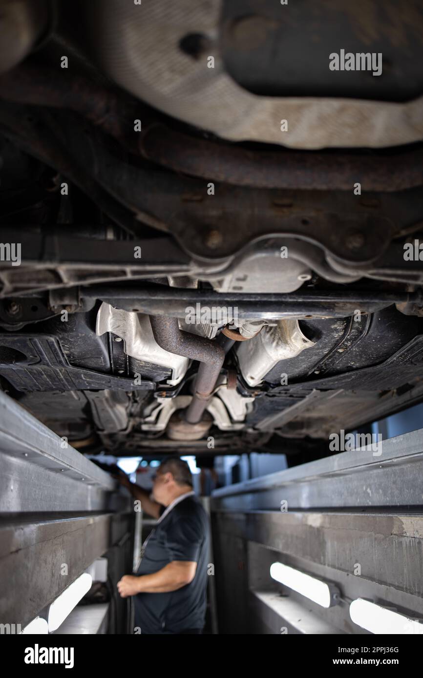 Kfz-Mechaniker unter einem Auto in einer Werkstatt/Garage (Flaches Freiheitsgrad/farbiges Bild) Stockfoto