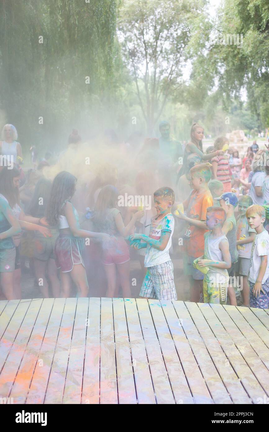 Lemberg, Ukraine - 18. Juli 2021: Color Holi Festival, eine Menschenmenge von Erwachsenen und kleinen Kindern werfen farbenfrohe Farben. Indianerfeiertag, Kinder laufen auf einer Holzbühne. Stockfoto