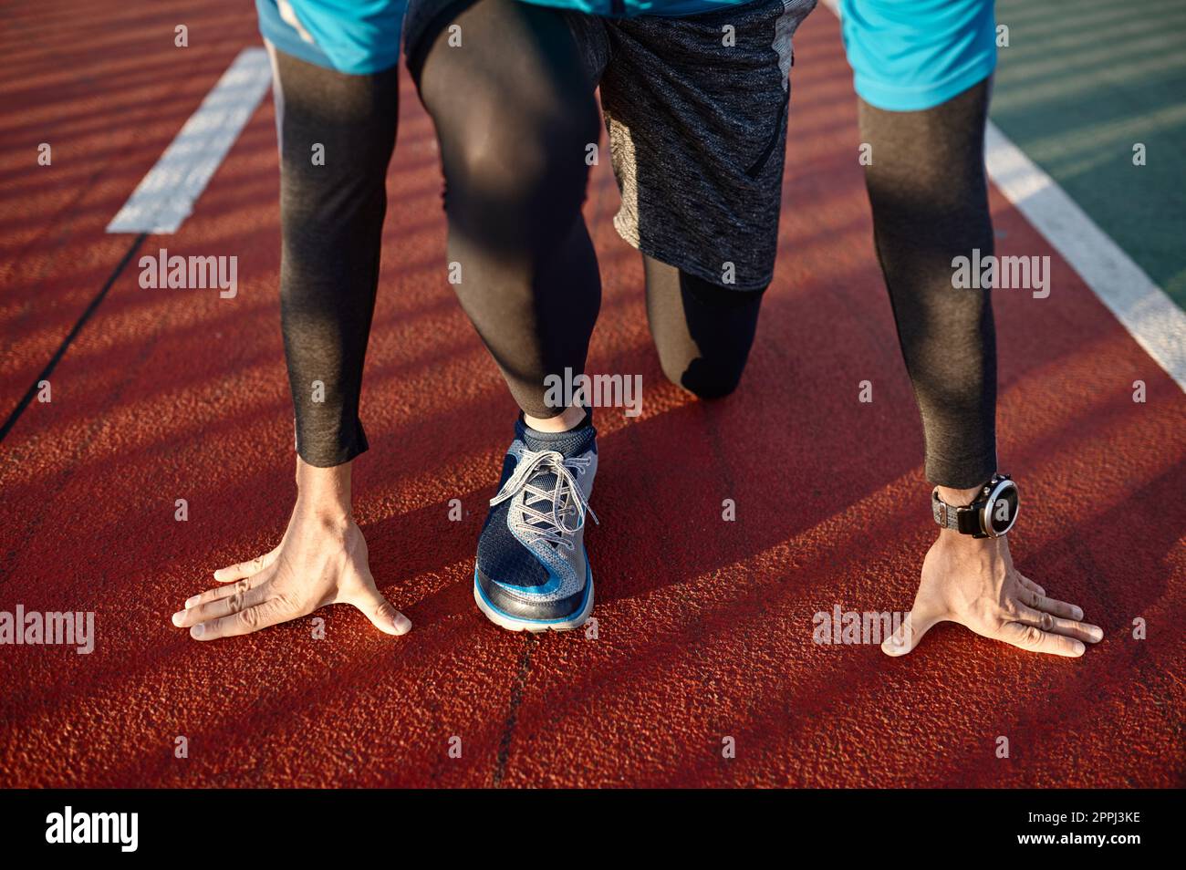 Speed Runner für Erwachsene in Startposition, bereit für das Laufen auf der Sportstrecke Stockfoto