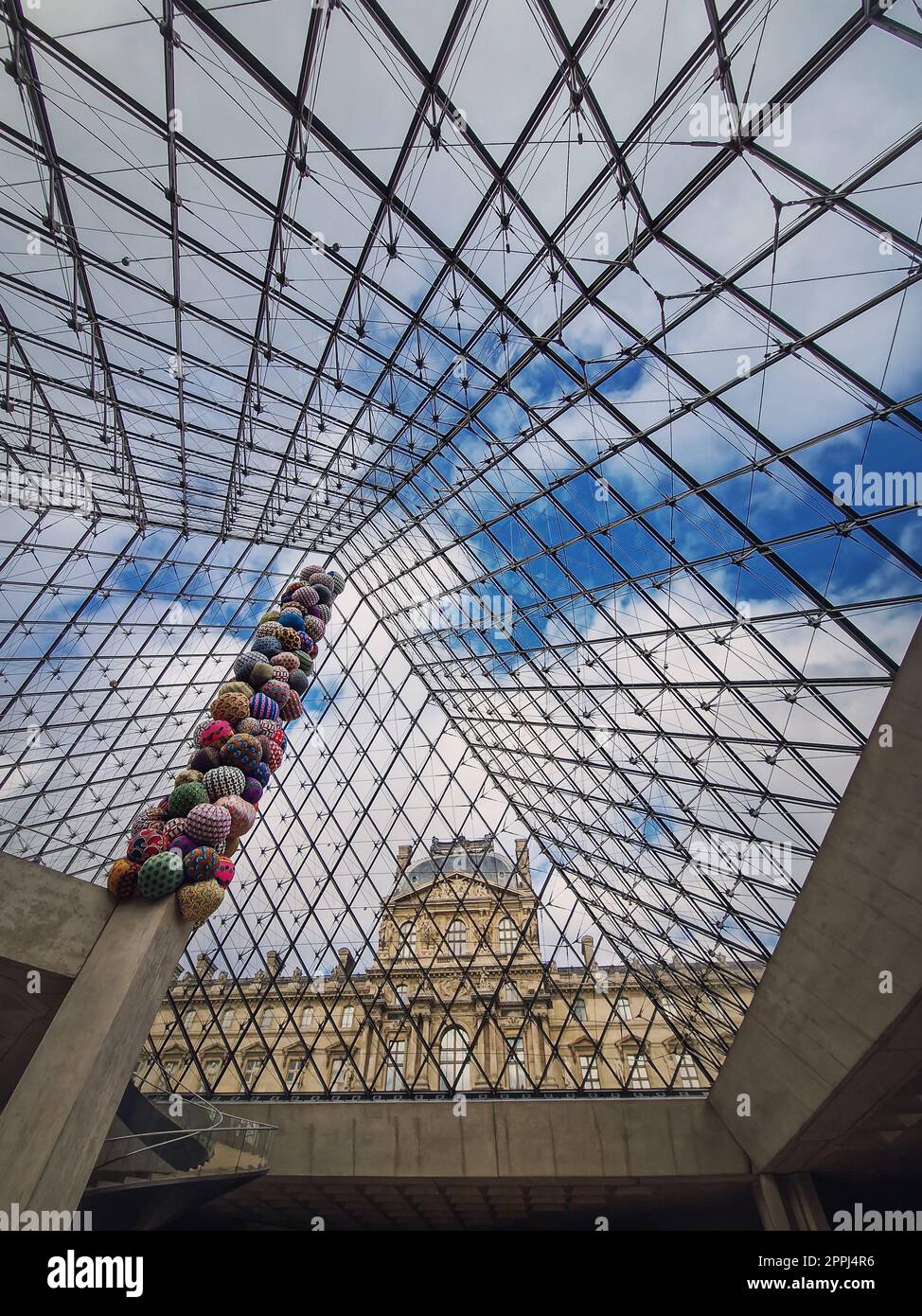 Unter der Glaspyramide des Louvre, vertikaler Hintergrund. Wunderschöne architektonische Details mit einer abstrakten Mischung aus klassischem und modernem Stil Stockfoto